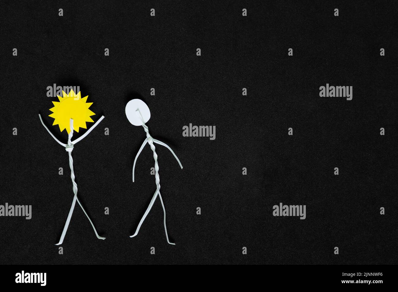 Étendre la positivité et être un rayon de soleil ou de lumière à d'autres personnes concept. L'homme colle la figure avec le soleil tandis que la tête applaudisse les autres en noir foncé Banque D'Images