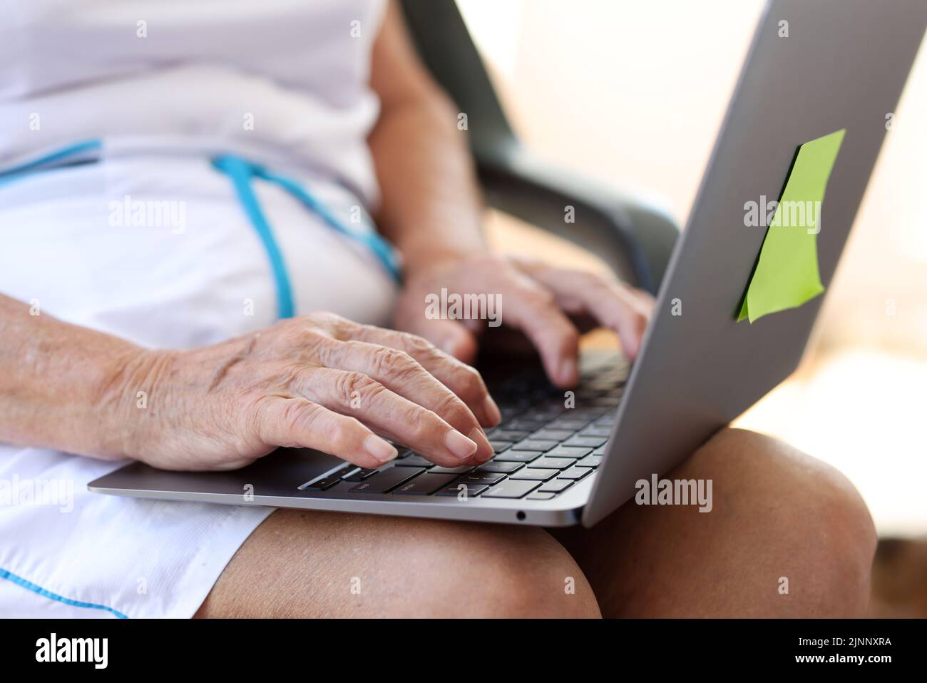 Une vieille femme tape les mains sur un ordinateur portable moderne Banque D'Images