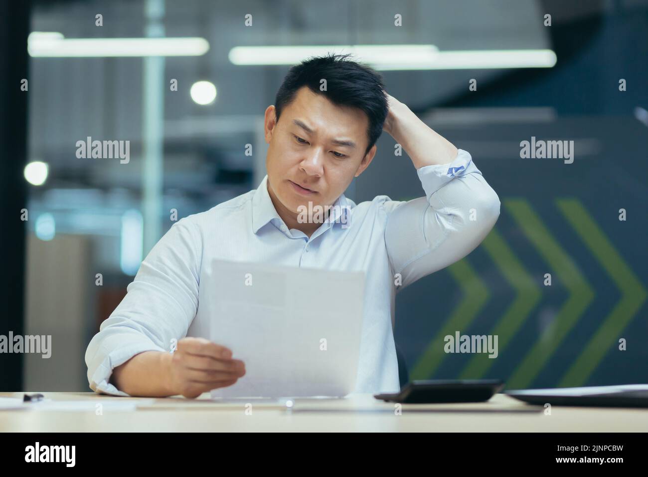 Homme d'affaires stressé tenant le visage avec ses mains parce qu'il a des problèmes. L'homme asiatique en faillite est assis avec un ordinateur portable et des documents sur le bureau au lieu de travail dans le bureau. Erreur d'affaires financière. Banque D'Images