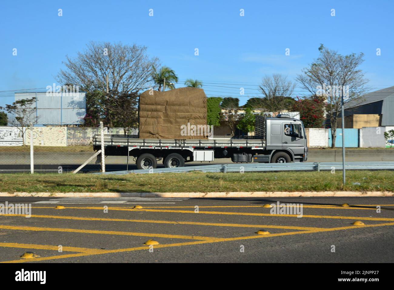 Camion de transport avec corps en bois sur l'autoroute brésilienne, vue latérale, arrière-plan avec flou intentionnel, asphalte premier plan avec panneaux de terre, autoroute dans ur Banque D'Images