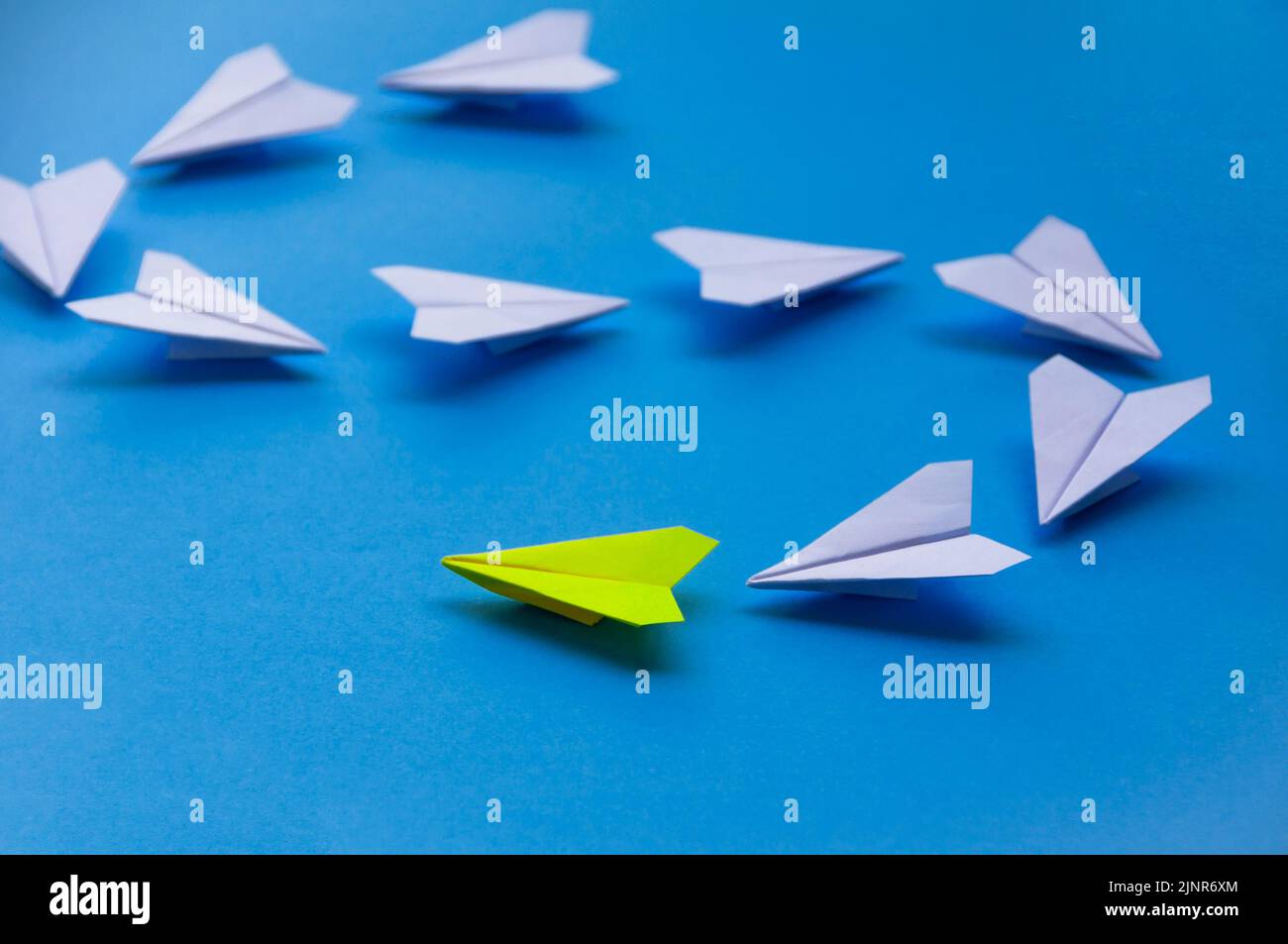 Papier jaune avion origami tête plans blancs sur fond bleu. Concept de compétences en leadership. Banque D'Images