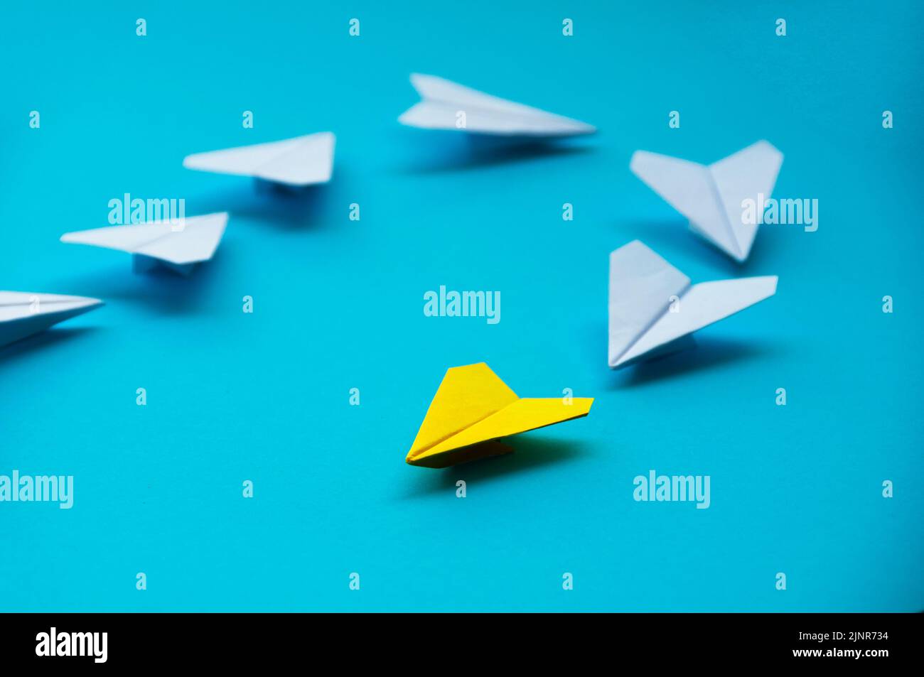 Papier jaune avion origami tête plans blancs sur fond bleu. Concept de compétences en leadership. Banque D'Images
