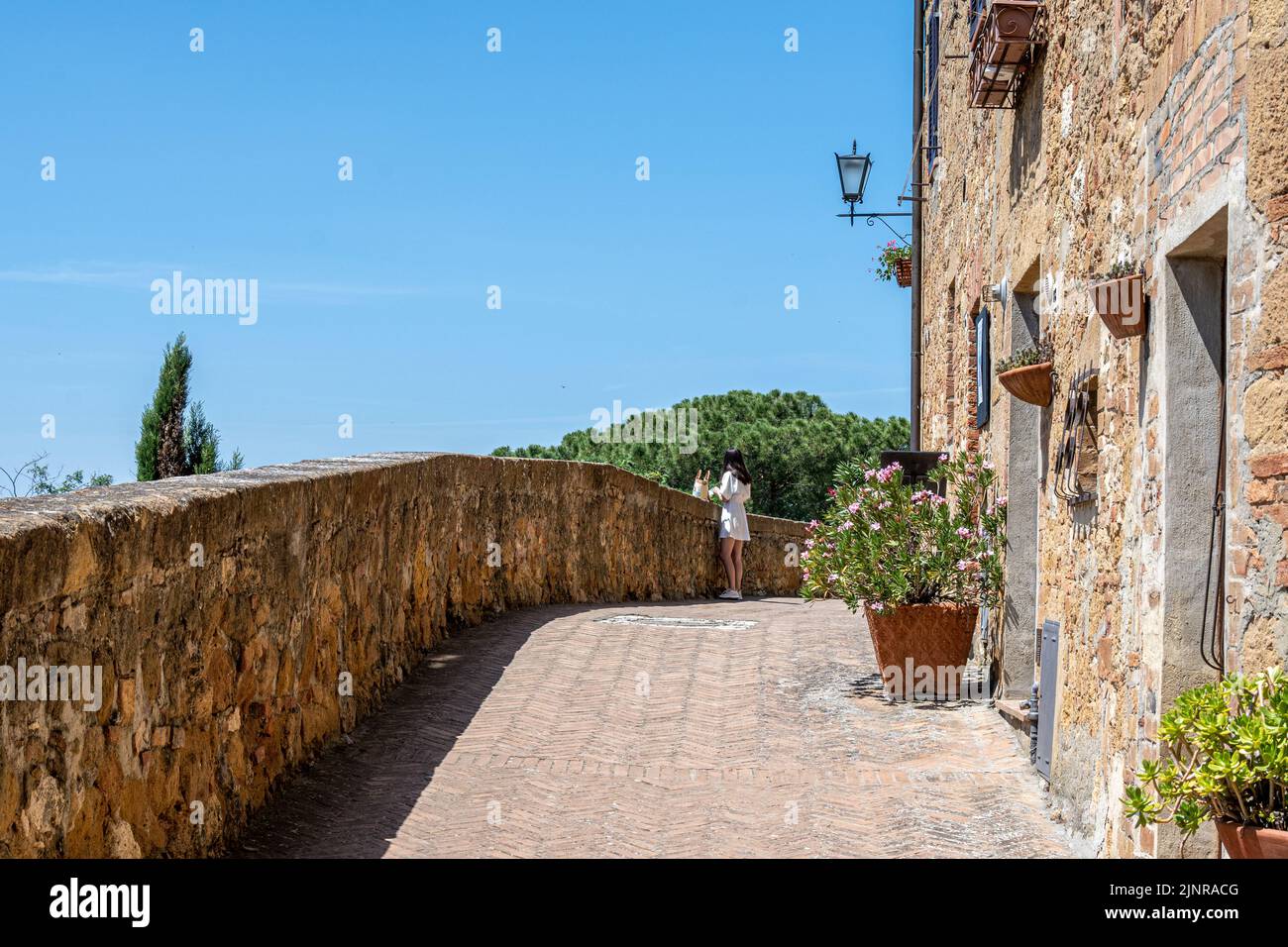Un touriste solitaire le long de la passerelle au-dessus des murs de Pienza, Toscane Banque D'Images
