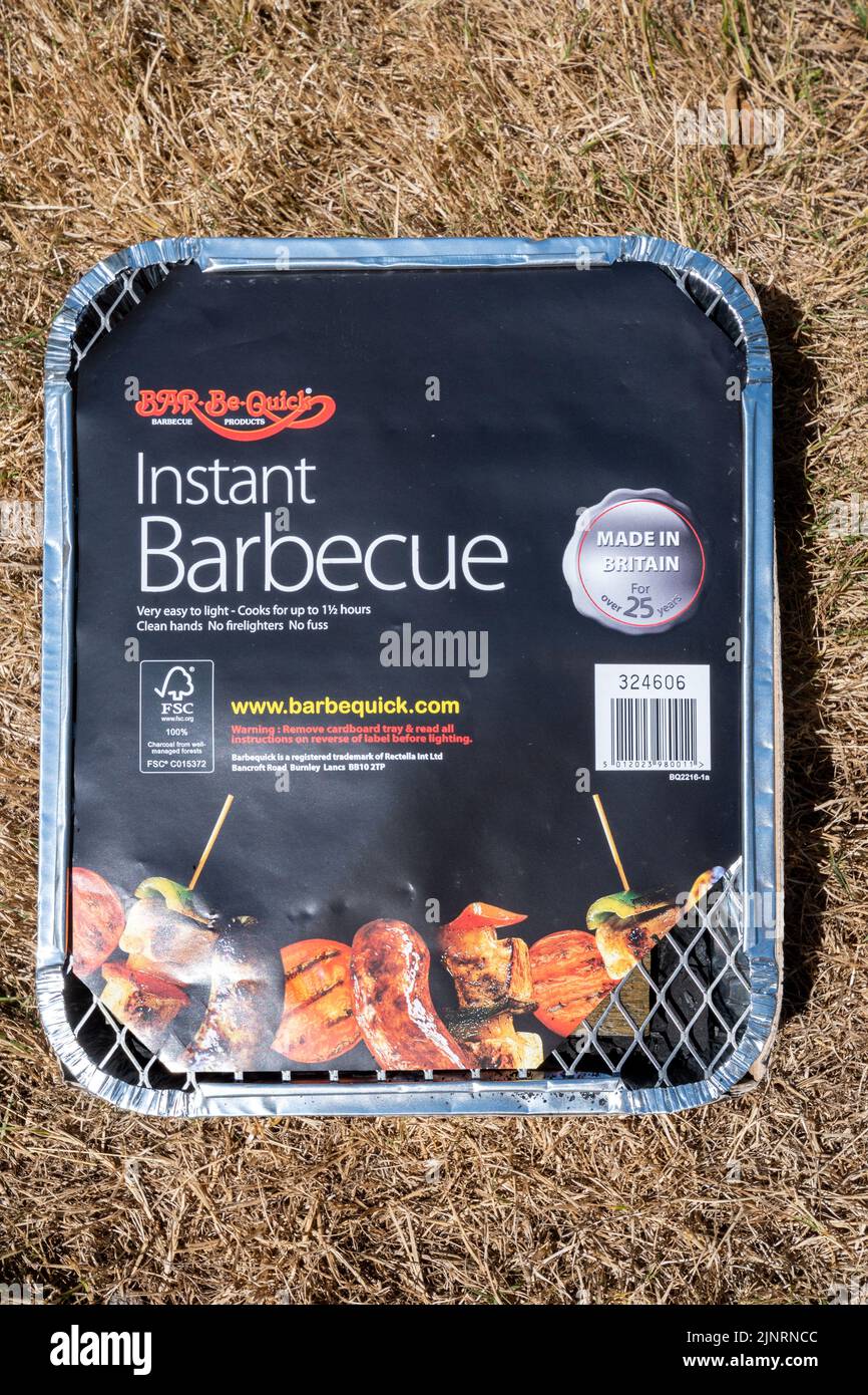 Barbecue jetable placé sur l'herbe brune parchée, la vague de chaleur et la sécheresse en août 2022, Royaume-Uni. Concept - risque d'incendie, d'incendie, d'incendie de forêt Banque D'Images