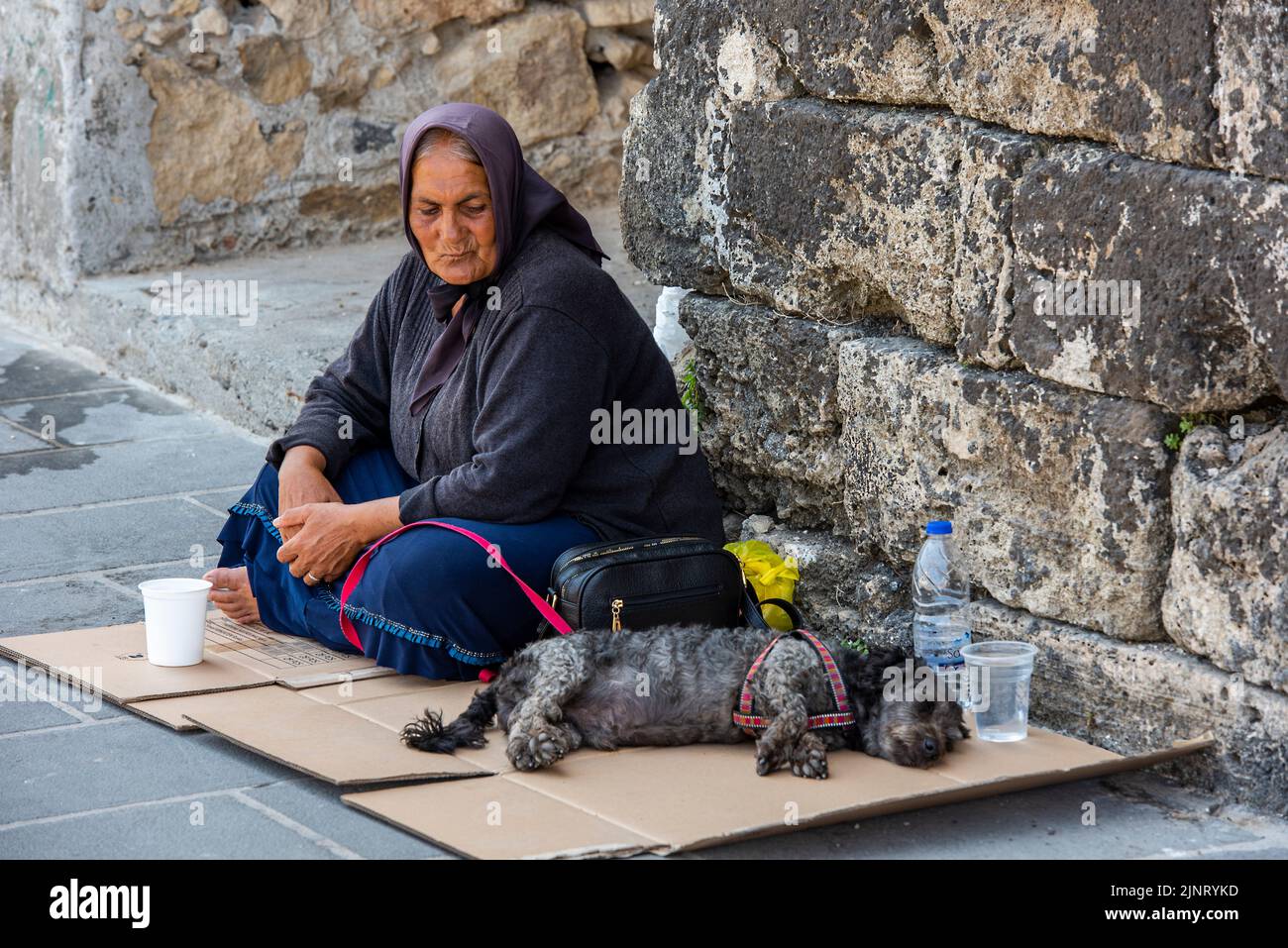 vieille dame vêtue de noir avec un chien implorant de l'argent dans les rues de chania sur l'île grecque de crète, mendiant femme dans les rues avec son chien Banque D'Images