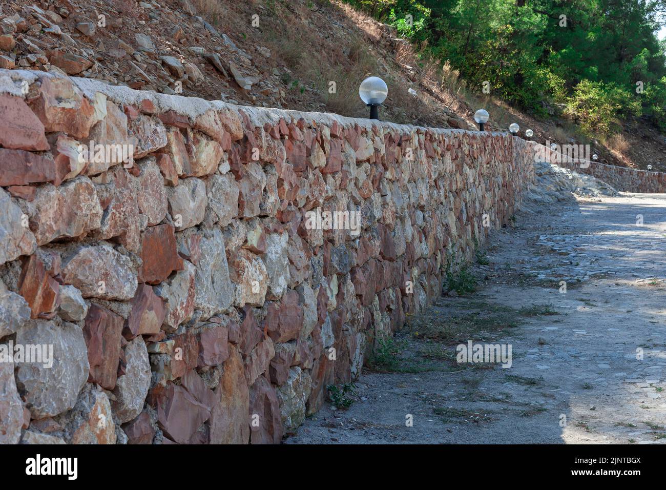 texture du mur en pierre. Lampes alignées pour éclairer un long mur en pierre. Banque D'Images