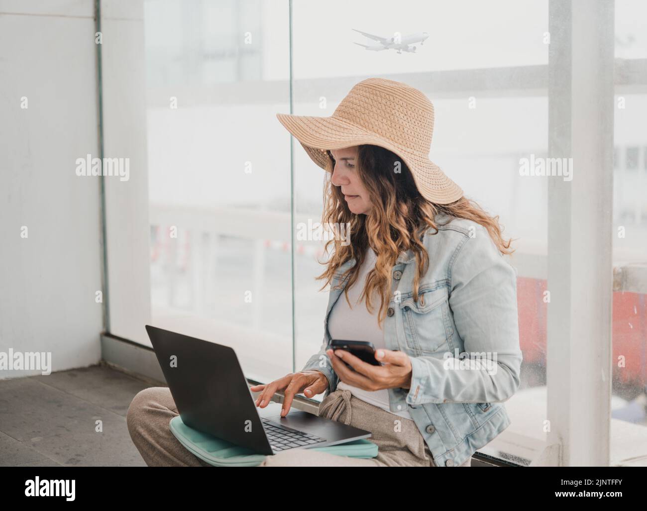 Femme utilisant des appareils près de la fenêtre de l'aéroport Banque D'Images
