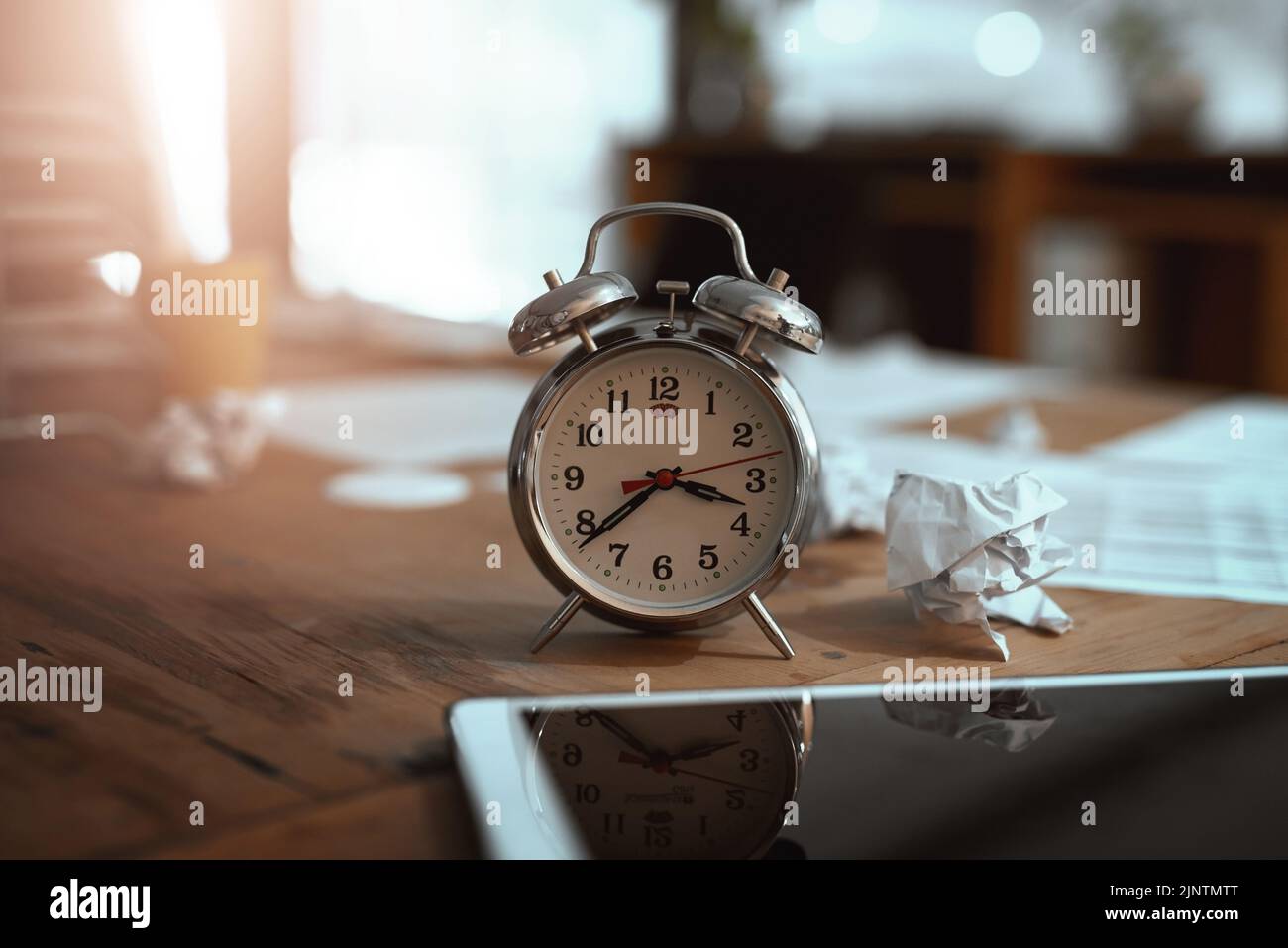 Le temps presse. Photo de la vie d'une horloge et papier froissé sur un bureau dans un bureau la nuit. Banque D'Images