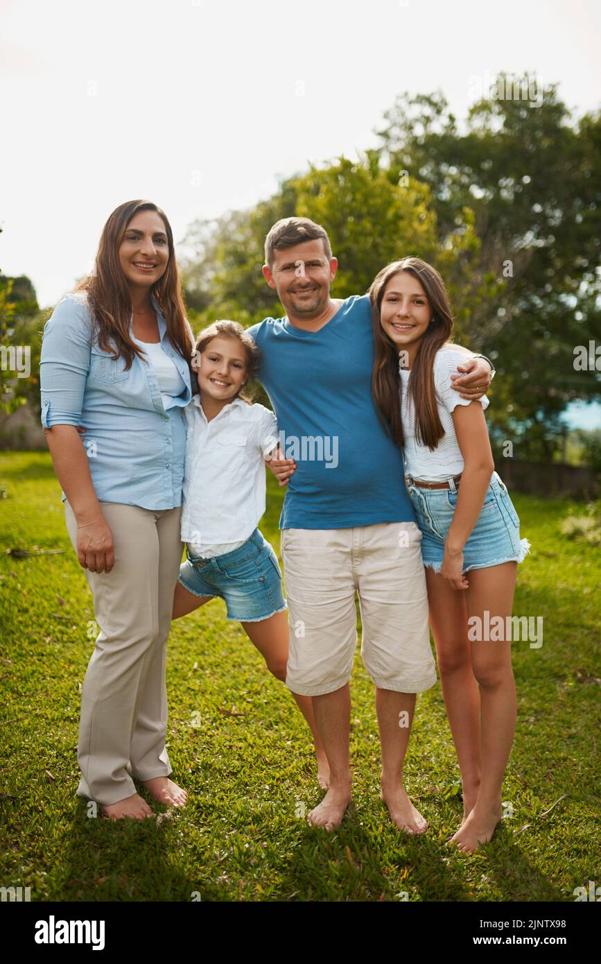 C'est une famille de livres d'images. Portrait d'une jeune famille de quatre personnes debout à l'extérieur. Banque D'Images