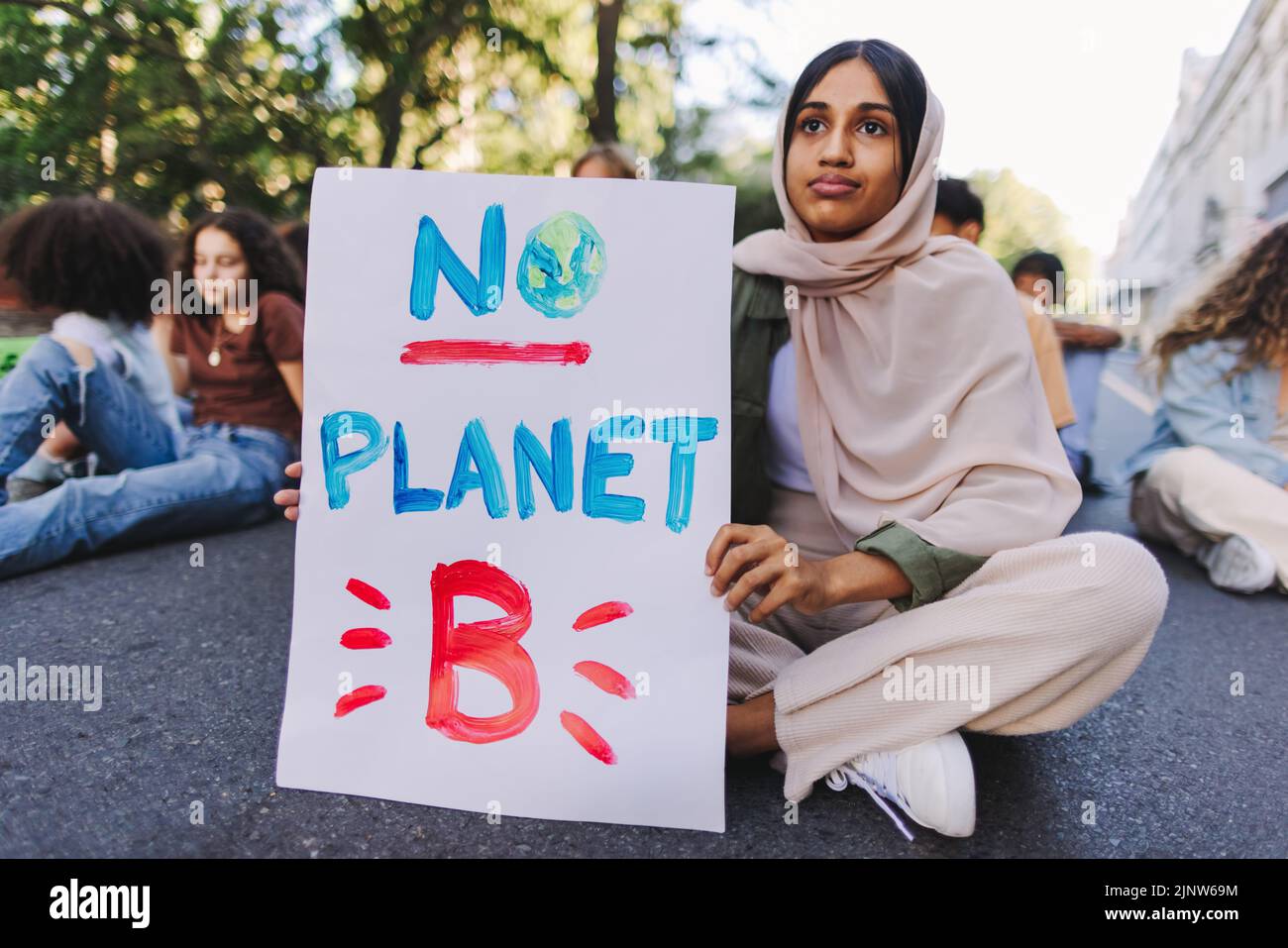Fille musulmane tenant une affiche « pas de planète B » lors d'une manifestation sur le changement climatique. Groupe de jeunes militants multiculturels protestant contre le réchauffement climatique Banque D'Images