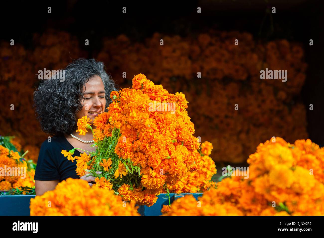 Une femme mexicaine sent un bouquet de fleurs marigolées (Flor de Muertos) pour les célébrations du jour des morts à Mexico, au Mexique. Banque D'Images