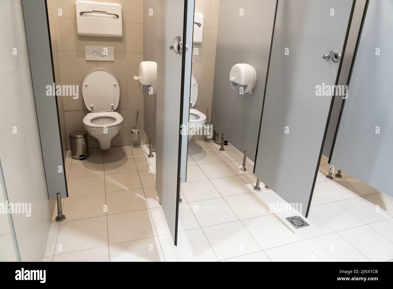 Paire de cabines de toilette classiques avec une porte ouverte dans une salle de bain publique Banque D'Images