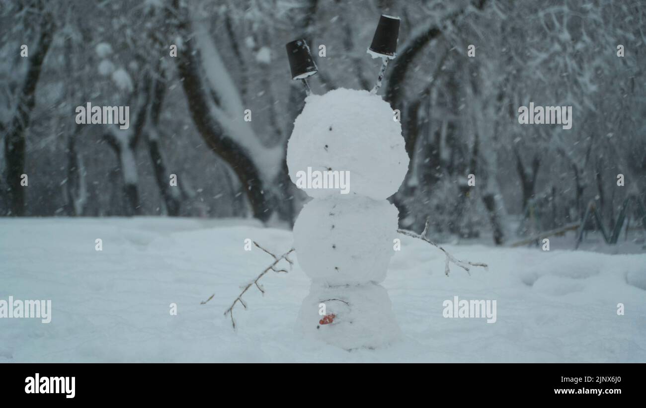 Joyeux bonhomme de neige drôle acrobat debout sur sa tête, sur fond d'une forte chute de neige. Bonhomme de neige se tient sur la tête Banque D'Images