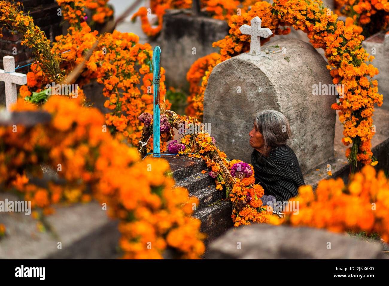 Une femme indigène Mixtec est assise parmi les tombes fleuries dans un cimetière lors des célébrations du jour des morts à Metlatónoc, au Mexique. Banque D'Images