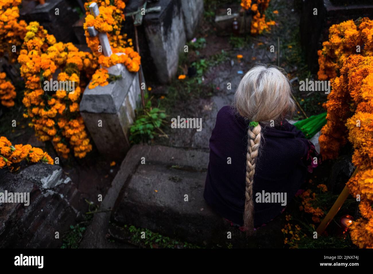 Une femme indigène Mixtec est assise parmi les tombes fleuries dans un cimetière lors des célébrations du jour des morts à Metlatónoc, au Mexique. Banque D'Images