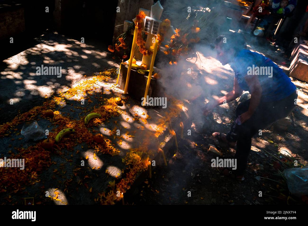 Une femme mexicaine, tenant un brûleur à encens fumant, effectue une purification d'une tombe pendant les célébrations du jour des morts à Tlapa de Comonfort, au Mexique. Banque D'Images