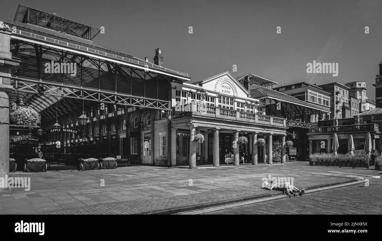 Une image en noir et blanc de quelques baigneurs de soleil dans le Covent Garden déserté de Londres pendant le premier confinement. Banque D'Images