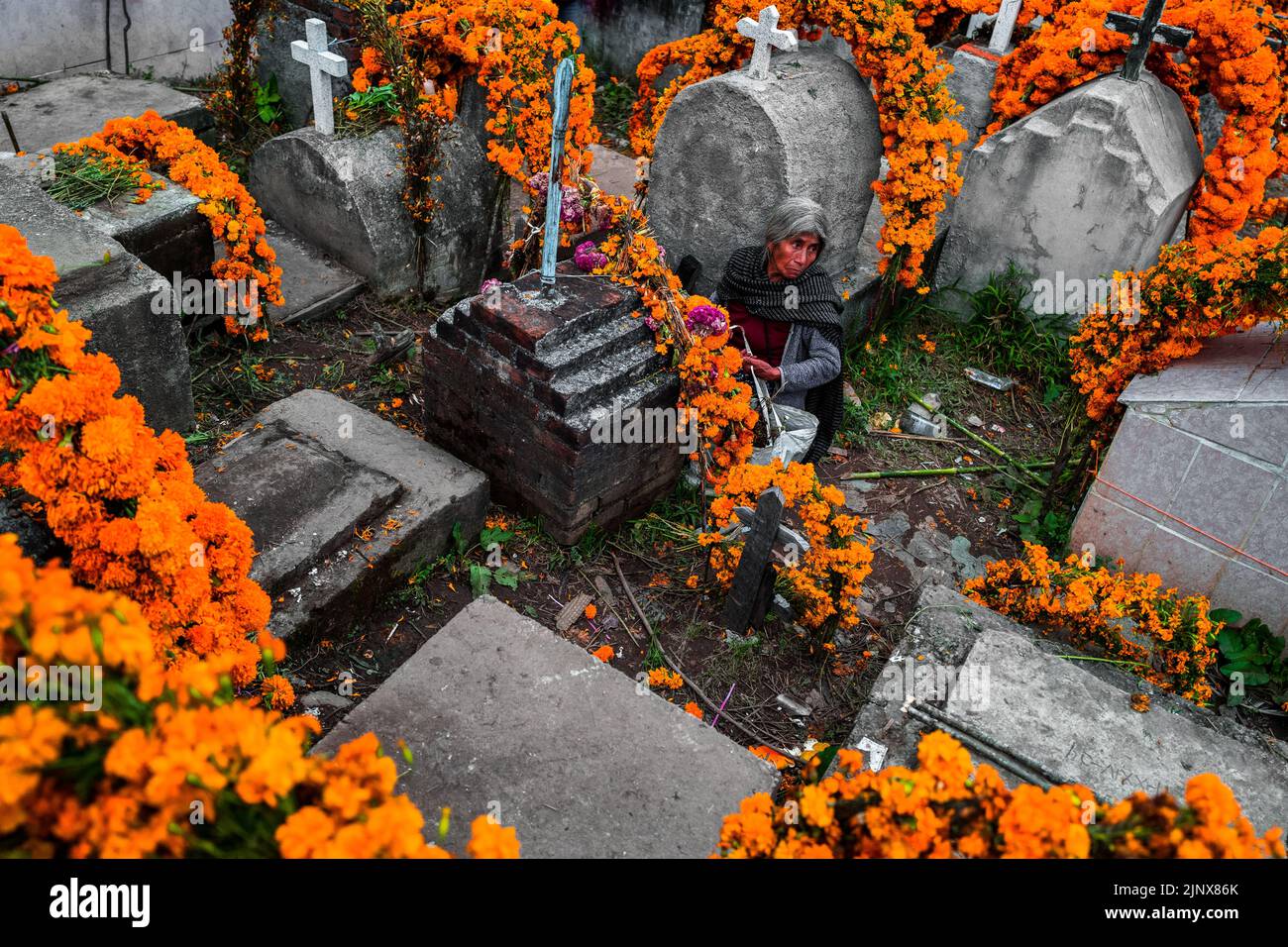 Une femme indigène Mixtec est assise parmi les tombes d'un cimetière lors des célébrations du jour des morts à Metlatónoc, Guerrero, Mexique. Banque D'Images