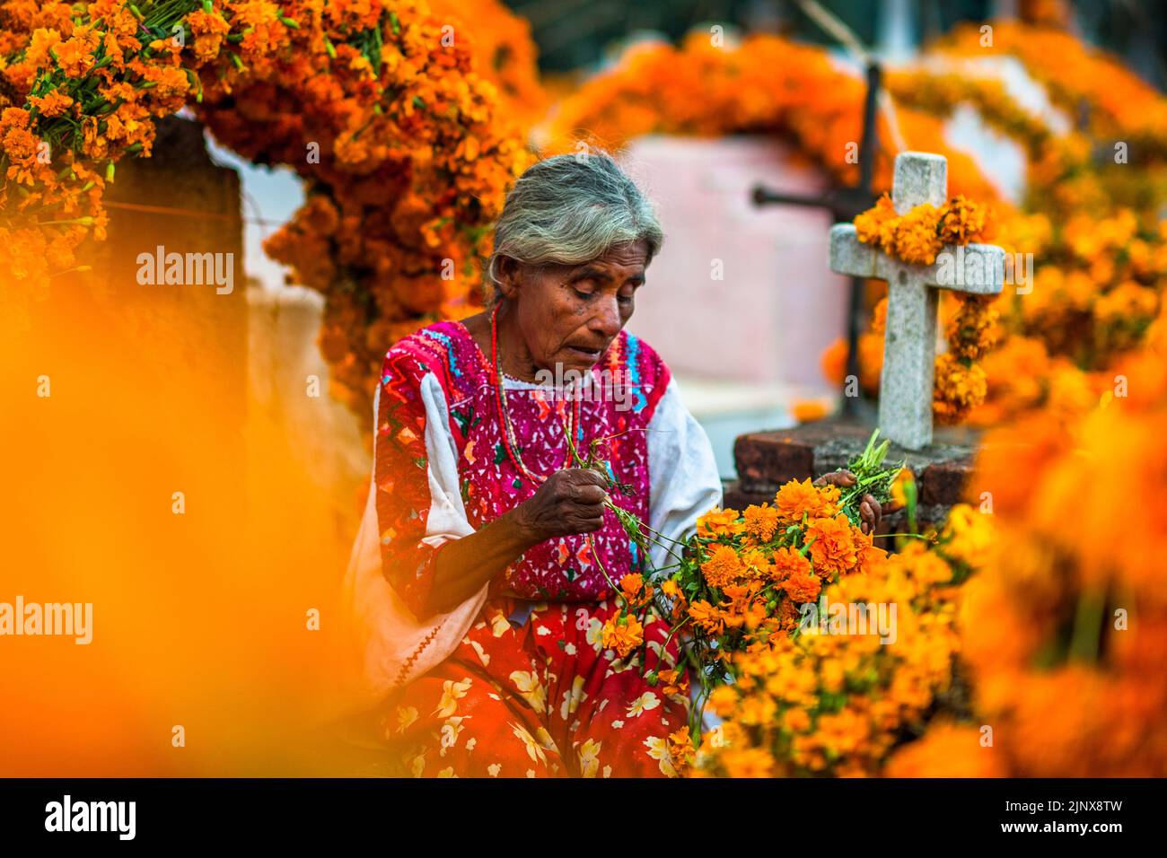 Une femme indigène Mixtec est assise parmi les tombes d'un cimetière lors des célébrations du jour des morts à Metlatónoc, Guerrero, Mexique. Banque D'Images