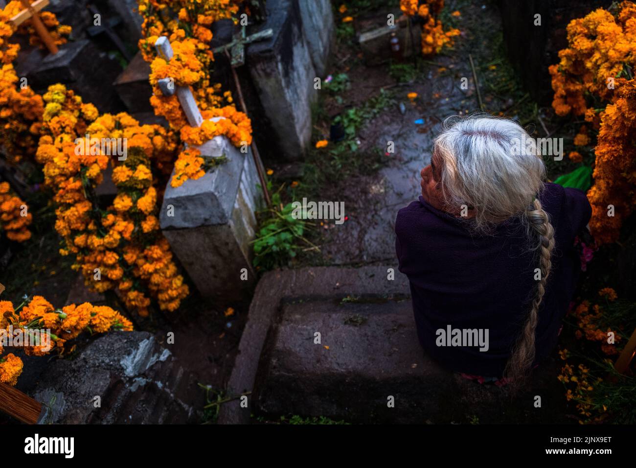 Une femme indigène Mixtec est assise parmi les tombes fleuries dans un cimetière lors des célébrations du jour des morts à Metlatónoc, au Mexique. Banque D'Images