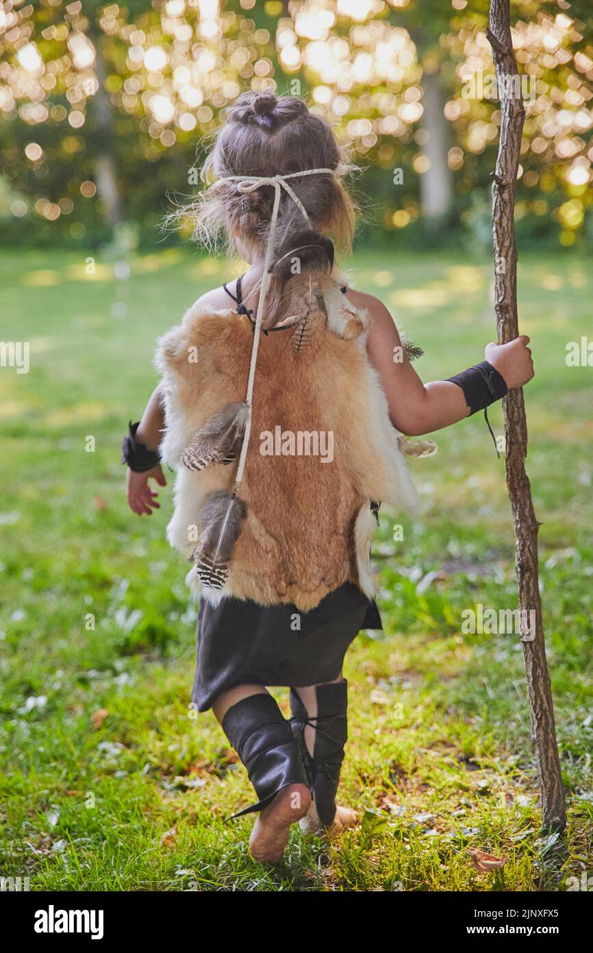 Mignon bébé habillé dans les vêtements de gens primitifs avec le personnel de combat Banque D'Images