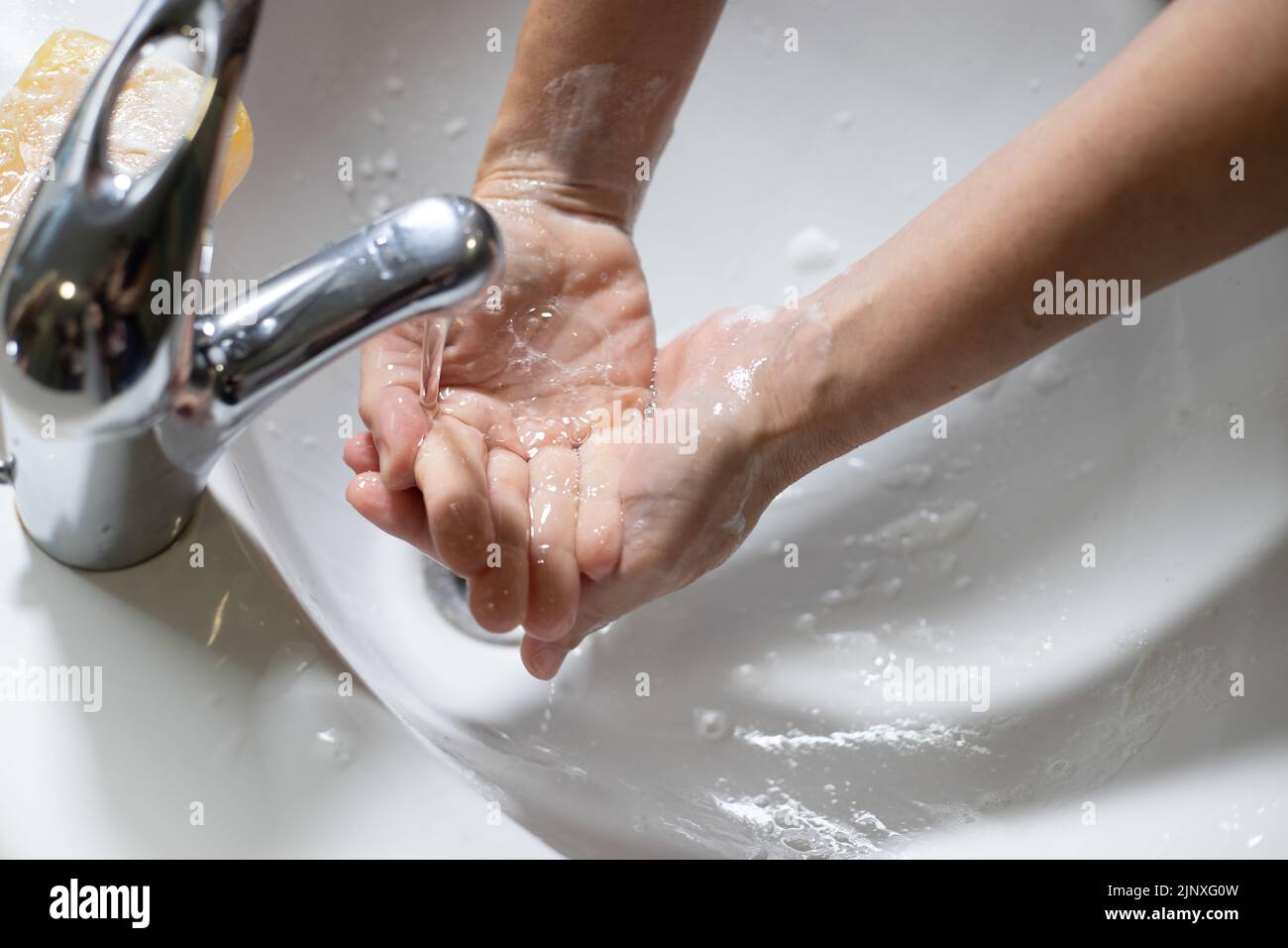 Mains caucasiennes rinçant dans le robinet de l'évier Banque D'Images