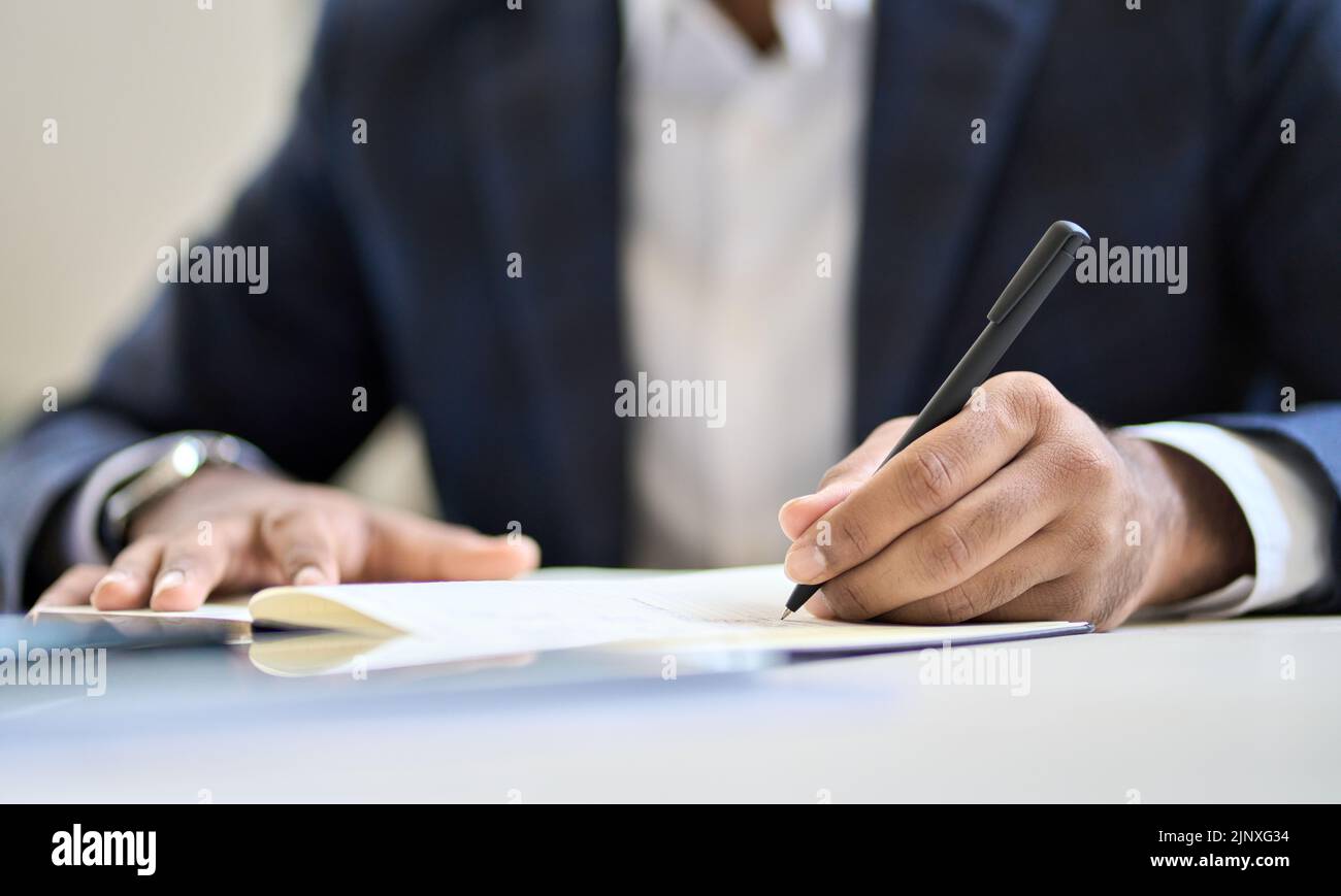 Homme d'affaires dirigeant portant un costume écrit dans un cahier ou un document légal. Banque D'Images