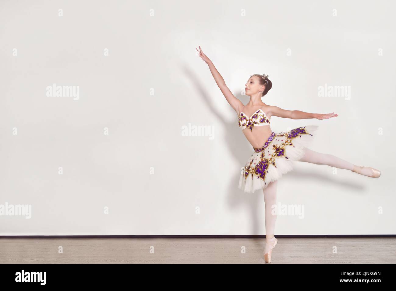 Une jeune ballerine effectue des exercices de ballet en studio sur fond blanc Banque D'Images