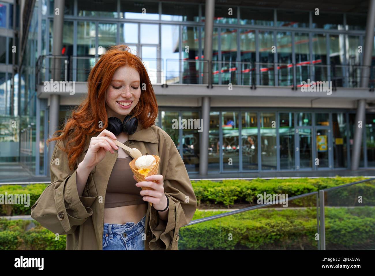 Cool Happy teen hipster fille debout dans la grande ville urbaine rue manger de la glace. Banque D'Images