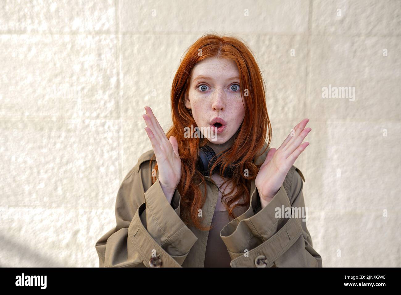 Choqué surprise adolescente redhead debout sur fond de mur urbain. Banque D'Images