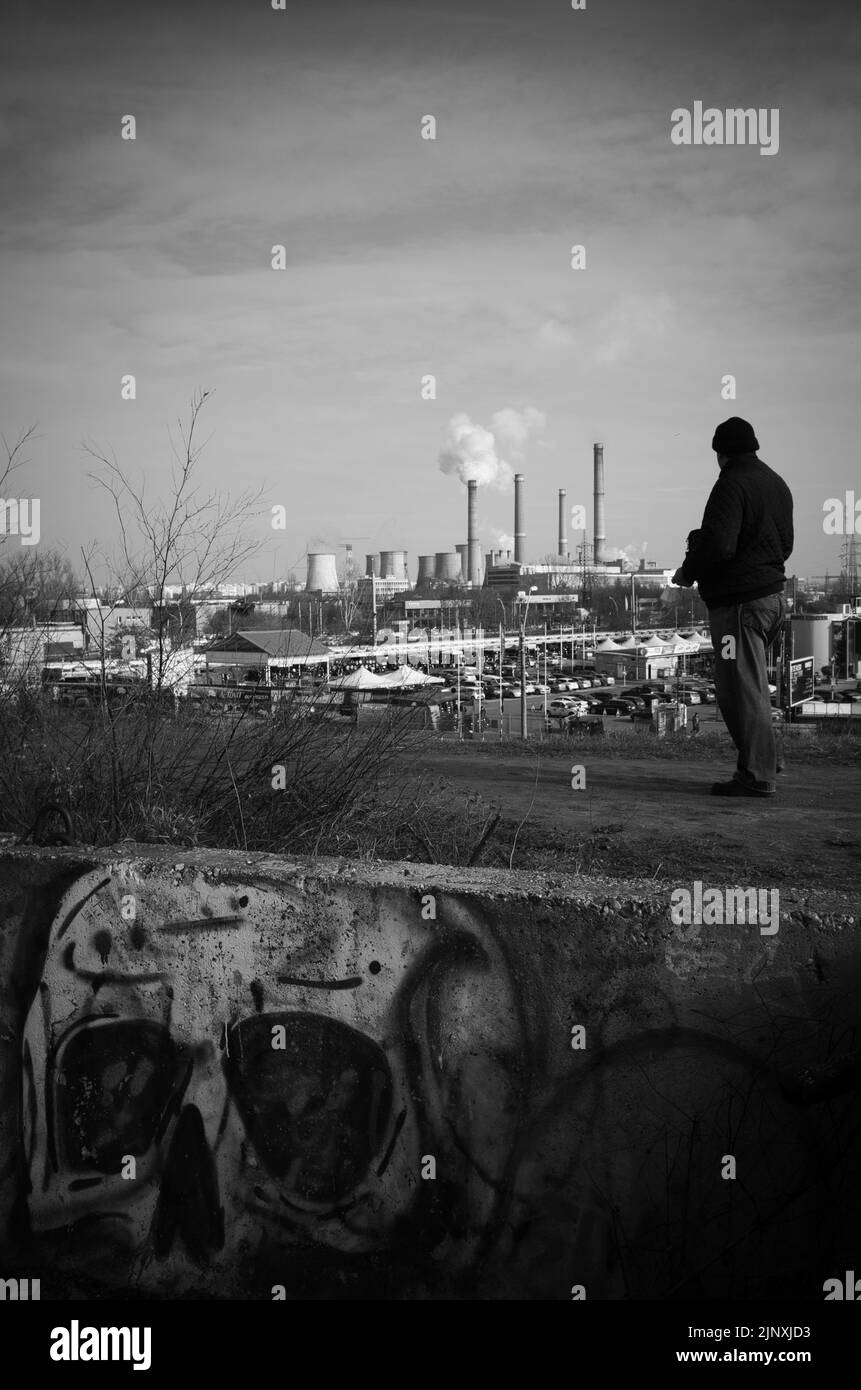 L'homme regarde la centrale électrique polluante avec des graffitis de crâne en premier plan Banque D'Images