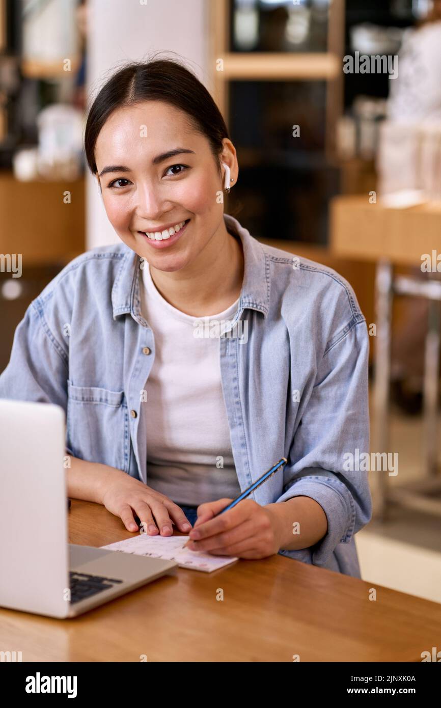 Jeune femme asiatique souriante étudiant en ligne à l'aide d'un ordinateur portable. Banque D'Images