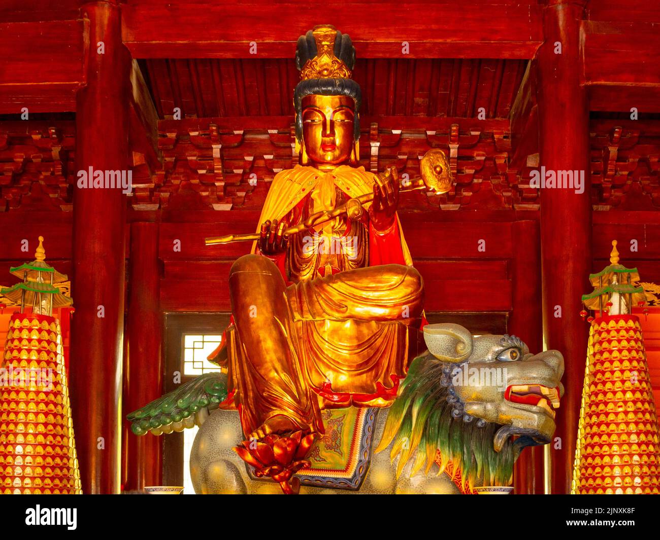 Figurine dorée avec une ressemblance femelle sur un lion. Symbole religieux traditionnel de la culture chinoise à l'intérieur d'un temple. Banque D'Images