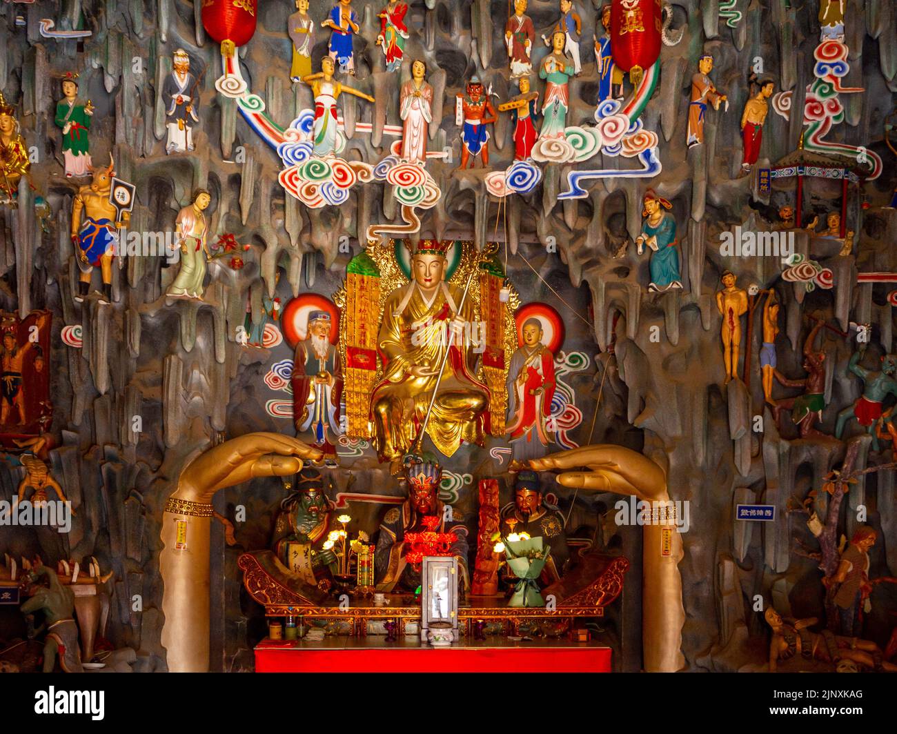 Vue de face d'un symbole religieux à l'intérieur d'un temple. La figure est de couleur dorée et entourée d'objets plus petits Banque D'Images