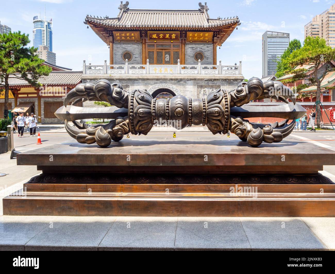 Sculpture ou art urbain métallique sur une place publique avec un bâtiment d'architecture chinoise traditionnelle en arrière-plan. Banque D'Images