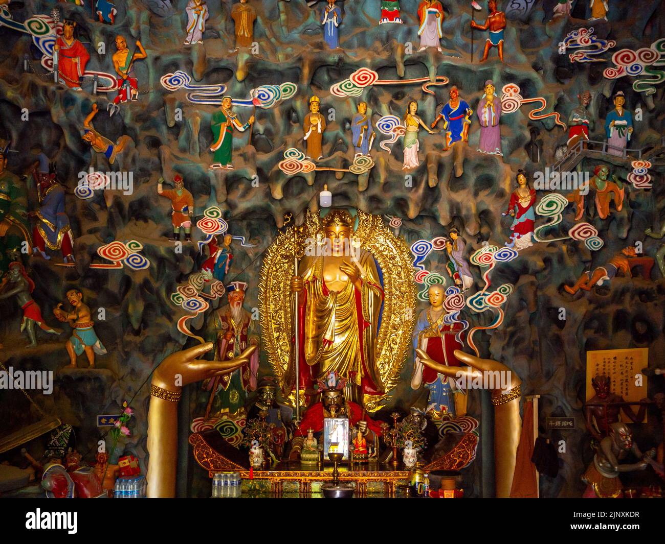 Vue de face d'un symbole religieux à l'intérieur d'un temple. La figure est de couleur dorée et entourée d'objets plus petits Banque D'Images
