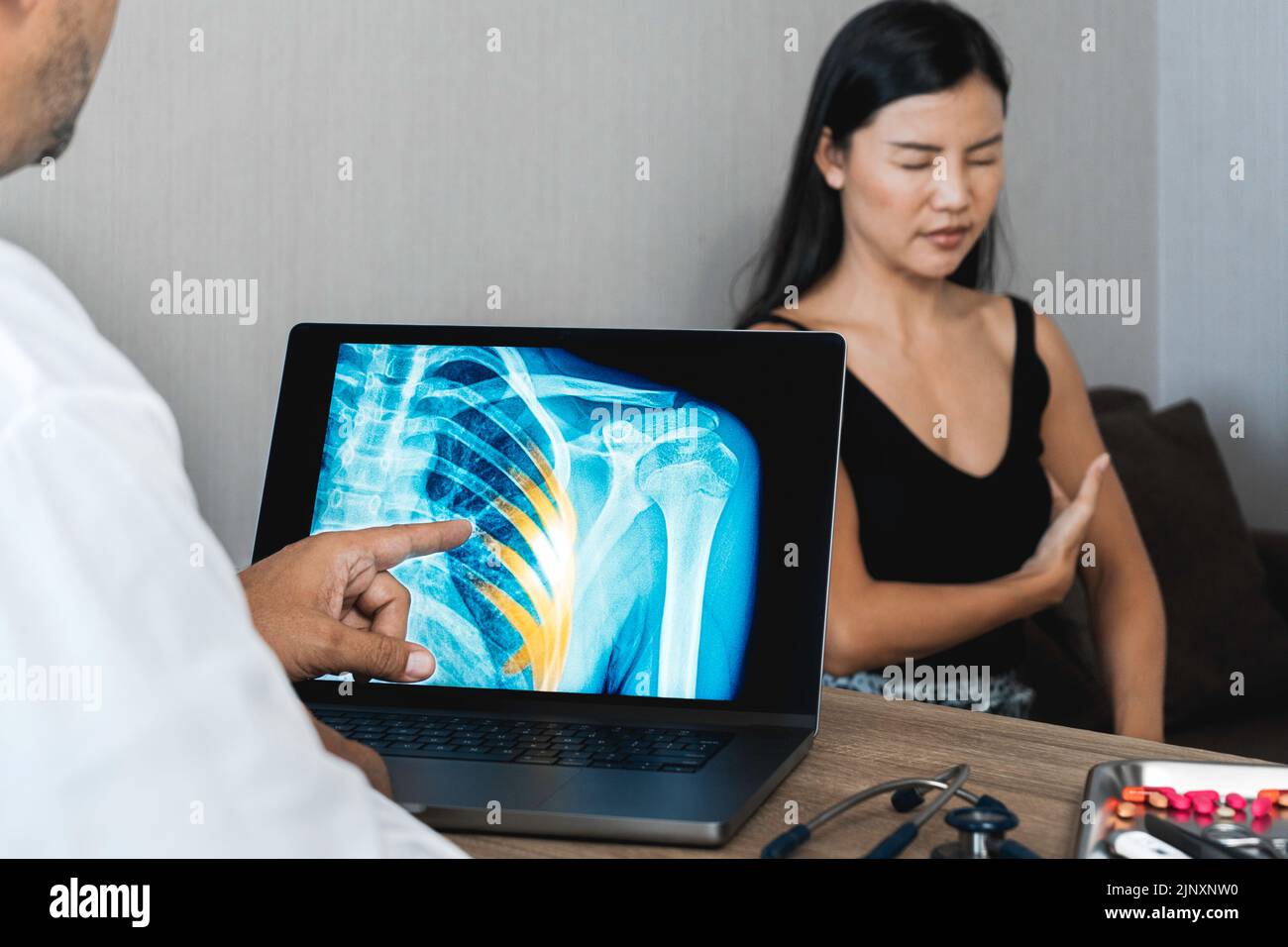 Médecin montrant une radiographie de la douleur dans les côtes d'une patiente Banque D'Images