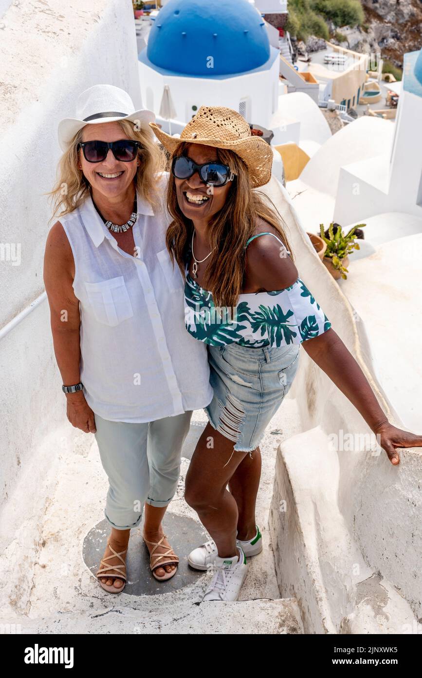 Deux touristes britanniques posent pour des photos à Un point de vue pittoresque dans la ville d'Oia, Santorini, les îles grecques, la Grèce. Banque D'Images