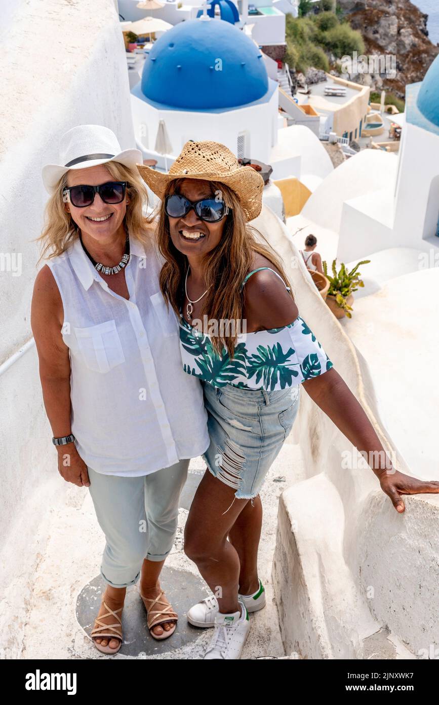 Deux touristes britanniques posent pour des photos à Un point de vue pittoresque dans la ville d'Oia, Santorini, les îles grecques, la Grèce. Banque D'Images