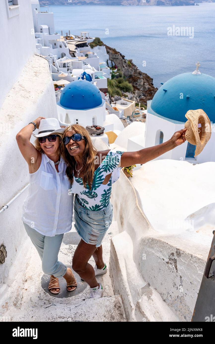 Deux touristes britanniques posent pour des photos à Un point de vue pittoresque dans la ville d'Oia, Santorini, les îles grecques, la Grèce. Banque D'Images