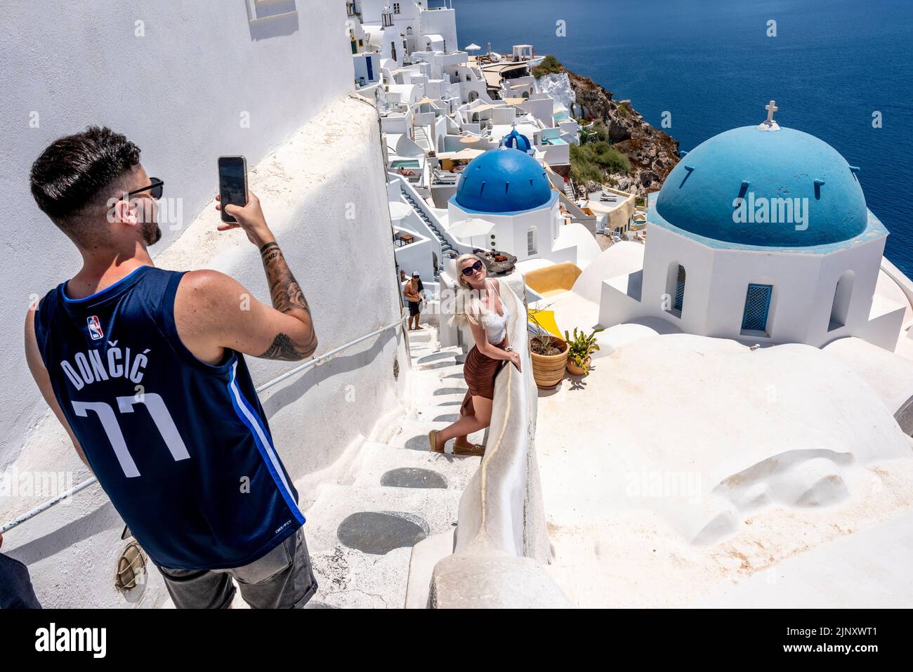Une jeune femme pose pour des photos à Un point de vue classique dans la ville d'Oia, Santorini, les îles grecques, la Grèce. Banque D'Images