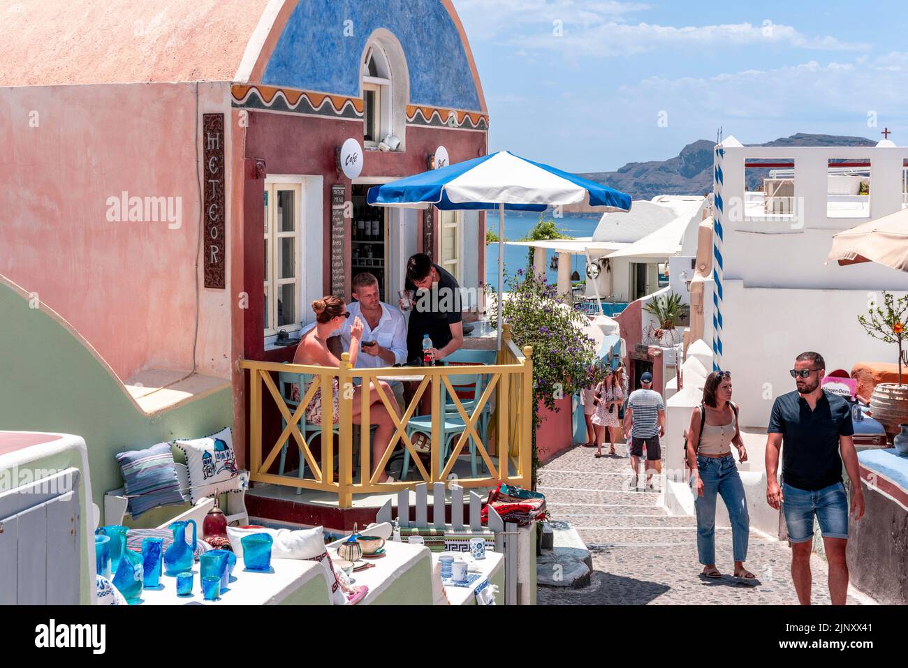 Un couple s'assoit avec des boissons sur la petite terrasse d'Un café dans la ville d'Oia, Santorini, les îles grecques, la Grèce. Banque D'Images