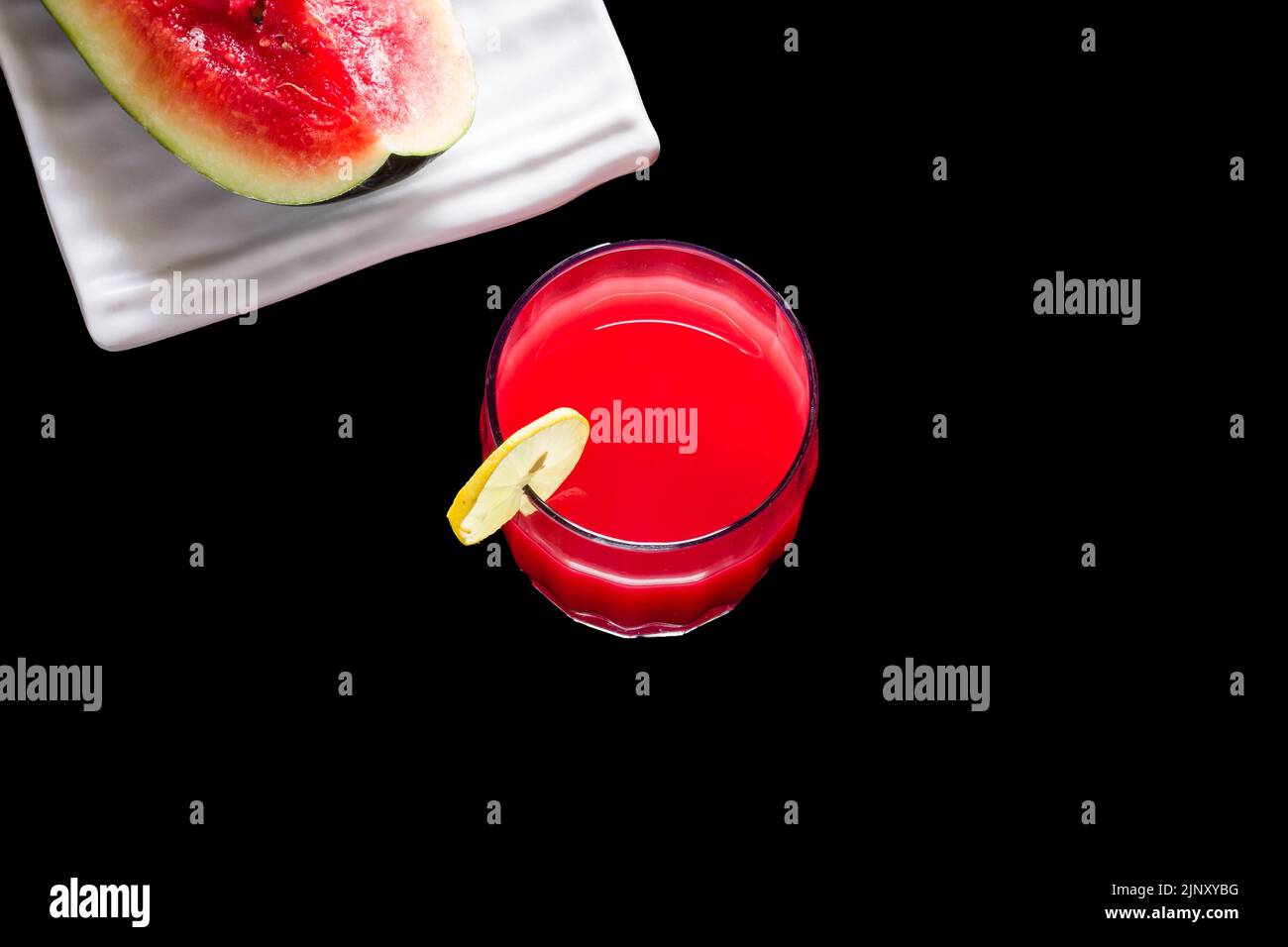 Verre simple de jus de fruit de pastèque réfrigéré. Sain mocktail frais garni avec une tranche de citron, isolé sur fond noir. Vue de dessus. Banque D'Images