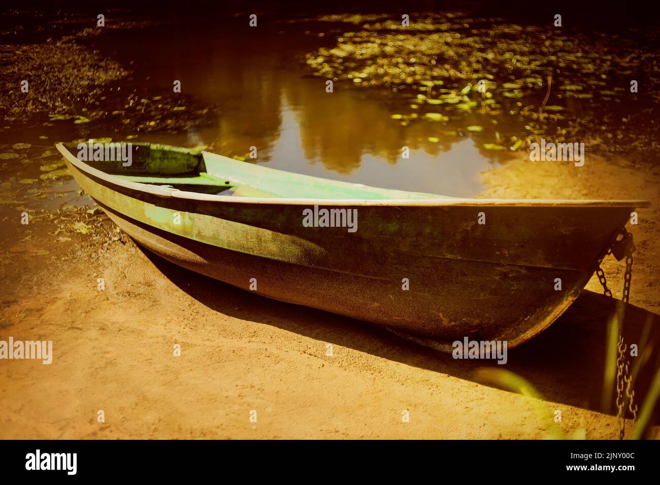 Un vieux bateau de pêche se trouve sur la rive sablonneuse d'une rivière sale. Sécheresse et réchauffement de la planète. Marée basse. Banque D'Images