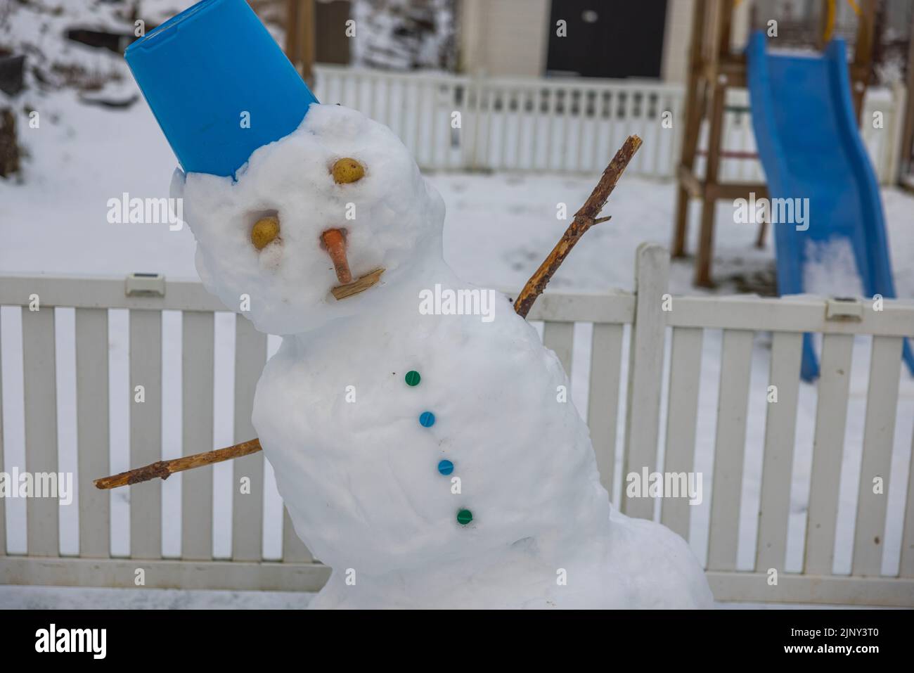 Vue rapprochée d'un bonhomme de neige drôle et instable en raison du temps chaud fait par les enfants dans le jardin d'hiver. Suède. Banque D'Images