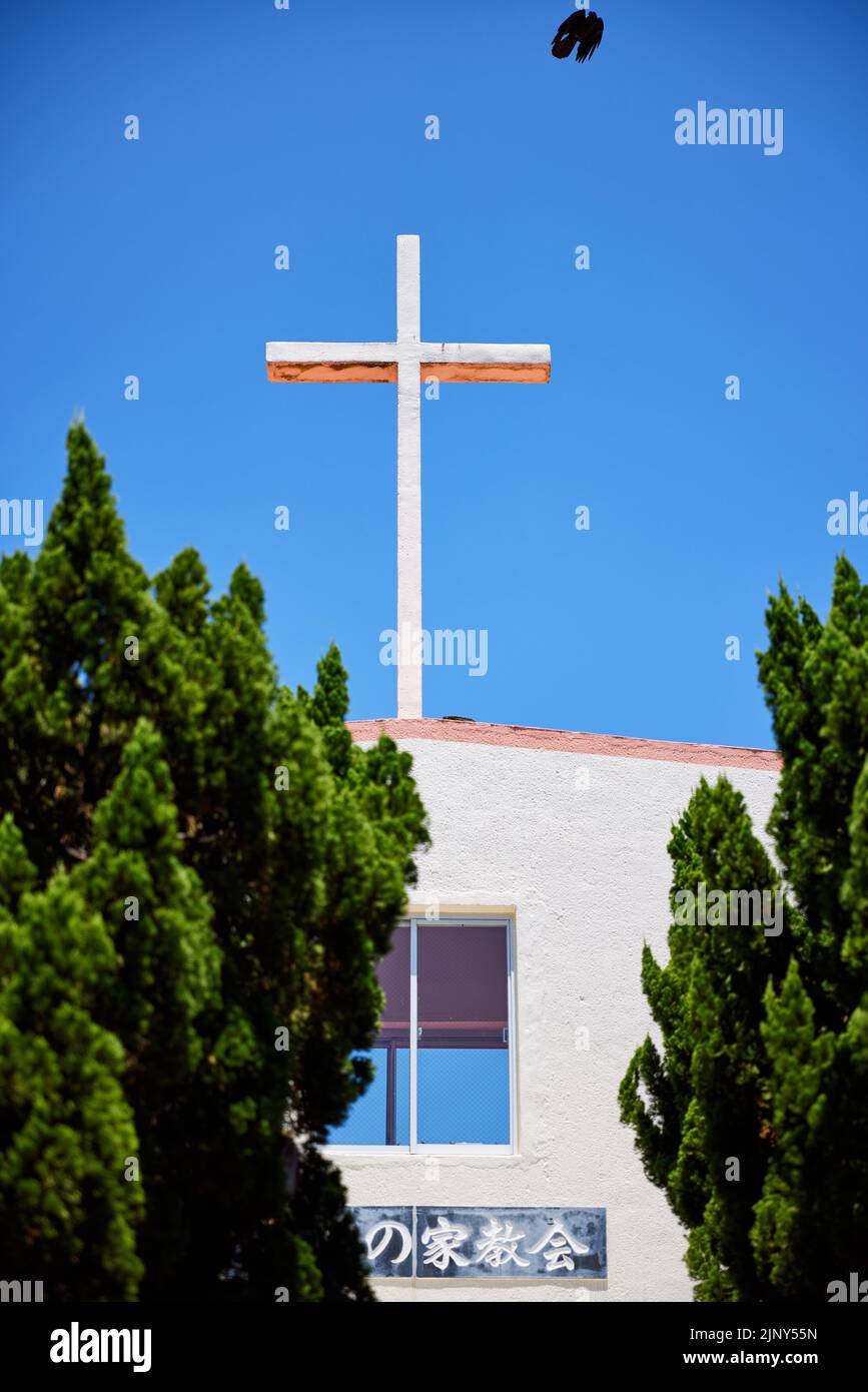 Crow partant de la croix sur la Maison de prière à la colonie de Leper d'Airakuen; Nago, préfecture d'Okinawa, Japon Banque D'Images