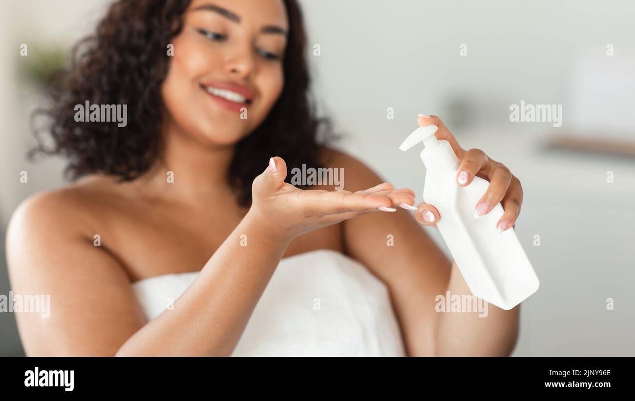 Concept nourrissant du corps. Une dame de chubby noire applique une lotion hydratante à la main, en faisant des soins de la peau Banque D'Images