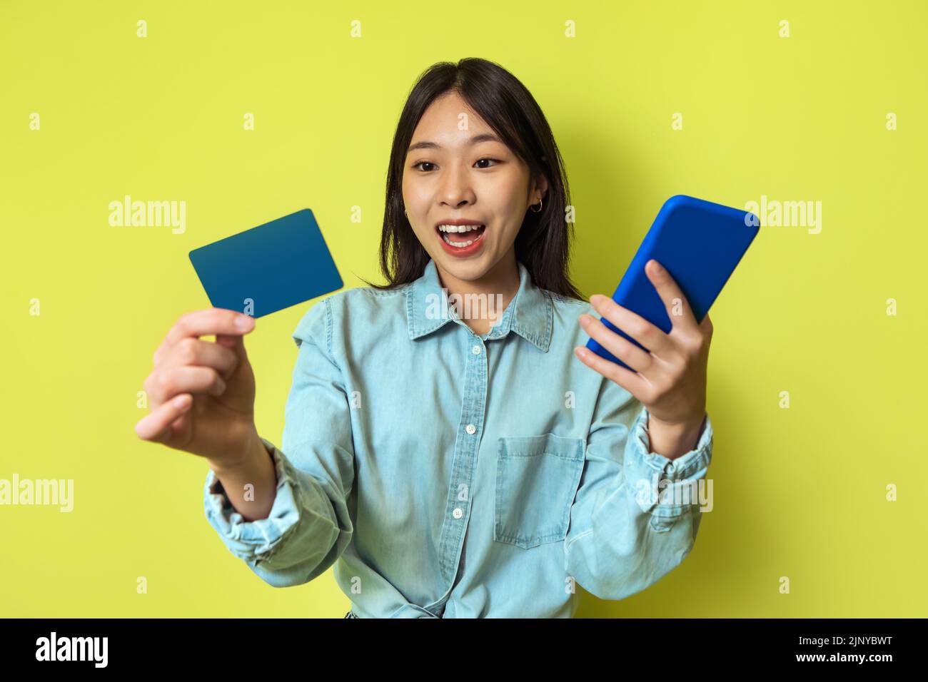 Korean Lady Holding téléphone et carte de crédit Shopping en ligne, Studio Banque D'Images