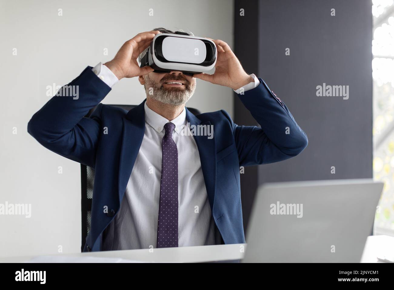 Bon homme d'affaires mature dans VR Headset Amusement at Workplace in Office Banque D'Images