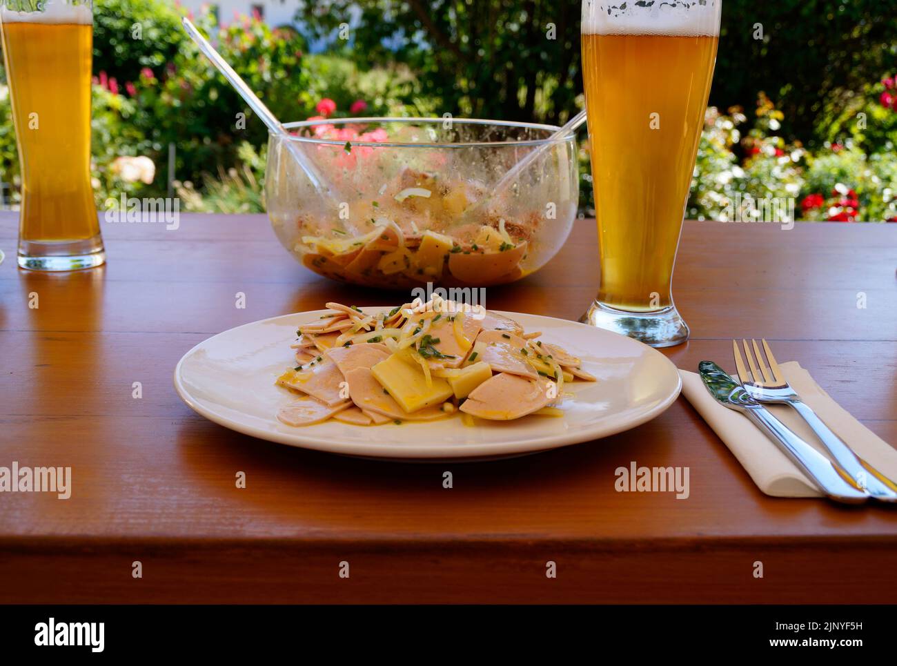 Un dîner allemand traditionnel, rustique et copieux dans un café en plein air avec quelques bières, une salade de saucisses suisses (Wurstsaplat) avec du fromage et des oignons Banque D'Images